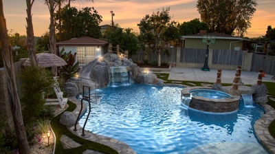 Freeform pool with spa in backyard at night Photo