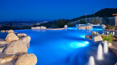 Illuminated freeform pool at night with water feature Photo