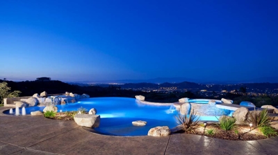 Illuminated freeform pool at night with patio Photo