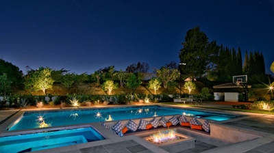 Sunken firepit seating area with illuminated pool at night Photo