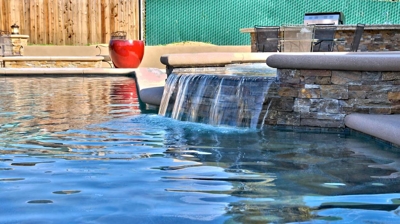 Spa attached to pool with waterfall into pool. Photo