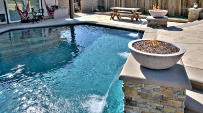 Fire feature on post with waterfall into pool. Photo