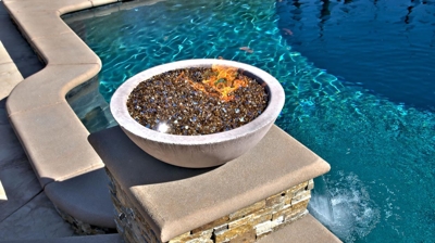 Fire feature bowl on post next to pool. Photo