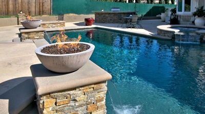 Fire feature bowl on post next to pool with spa. Photo