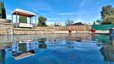 Covered bench swing next to pool with waterfall and fire features. Photo