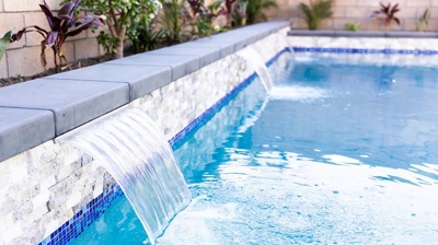 Backyard pool in an L-shape, featuring captivating water elements. Photo