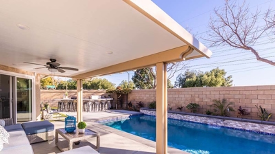 Backyard patio boasting an L-shaped pool with mesmerizing water accents. Photo