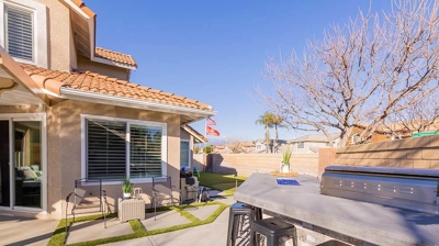 An outdoor patio equipped with a barbecue grill, seating arrangements, and grass pavers. Photo