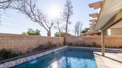 L-shaped backyard pool adorned with water features. Photo