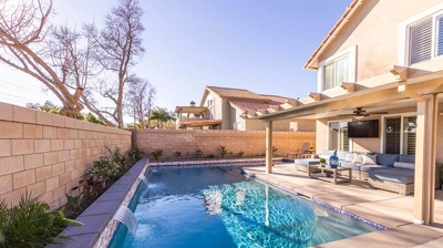 L-shaped pool in the backyard with enchanting water features. Photo
