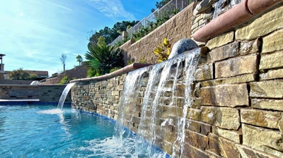 An idyllic backyard escape boasting waterfalls and a shimmering swimming pool. Photo