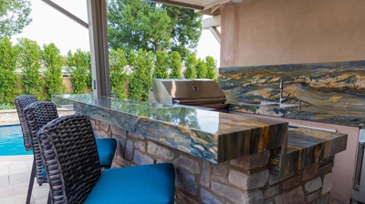 Poolside gourmet retreat with built-in grill, sink, stove, and storage solutions. Photo