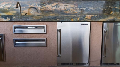 Exterior culinary hub beside the pool boasting a grill, sink, stovetop, and storage amenities. Photo