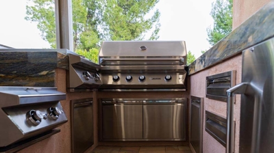 Poolside culinary oasis complete with grill, sink, stove, and storage. Photo
