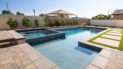 Contemporary backyard oasis featuring an integrated spa and pool bordered by grass pavers. Photo