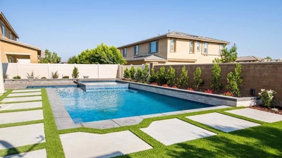 Sleek backyard retreat boasting a spa-pool combination encircled by lush grass pavers. Photo