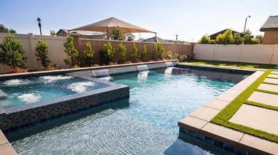 Cutting-edge outdoor living space featuring a pool with a built-in spa, surrounded by grass pavers. Photo