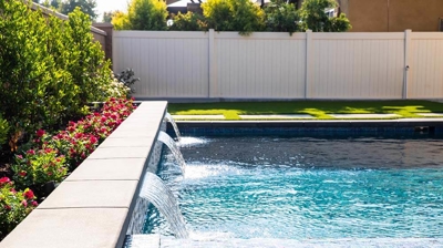 Sophisticated outdoor oasis showcasing a pool with a waterfall. Photo