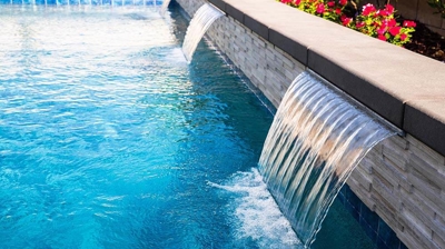 Chic outdoor space with a pool and spa combination with waterfalls. Photo