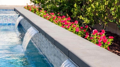 Chic outdoor space with a pool and spa combination with waterfalls. Photo