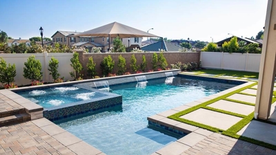 State-of-the-art backyard sanctuary showcasing a pool-spa duo embraced by turf pavers. Photo