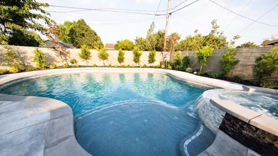 In-ground backyard pool complemented by an above-ground spa for added luxury. Photo
