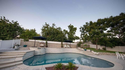 Elevated outdoor sanctuary showcasing a pool and spa surrounded by stone accents and steps. Photo