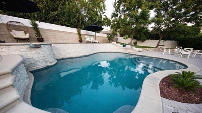 Backyard oasis with multiple levels housing a pool, spa, and bordered by pool coping. Photo