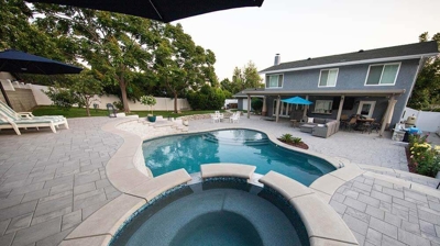 Backyard retreat featuring tiered levels with a pool and spa embraced by stone accents and stairs. Photo