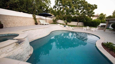 Multi-tiered outdoor haven showcasing a pool and spa surrounded by stone features and stairways. Photo