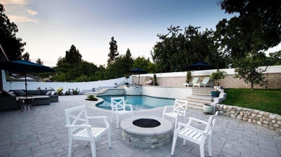 A conversation area white white chairs and a fire pit. Photo