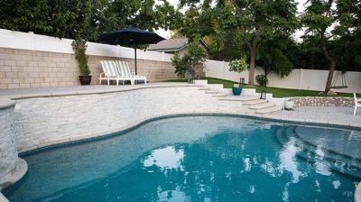 Backyard sanctuary boasting multi-level landscaping with a pool, spa, and stone-lined stairs. Photo
