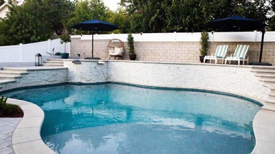 Backyard escape with tiers featuring a pool, spa, and stone-framed stairs. Photo