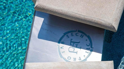 A logo for Pro Fab Tech LLC on a spa overflow section of a spa wall. Photo