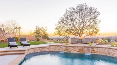 A tranquil outdoor retreat featuring a pool, grassy area, fire pit, and comfy seating. Photo