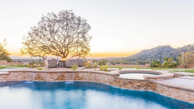 An idyllic outdoor sanctuary highlighting a pool, spa, seating and a spa. Photo
