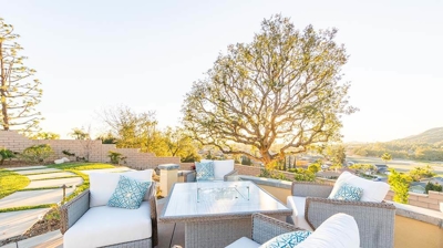 A picturesque backyard retreat with greenery, a fire pit, and inviting seating. Photo