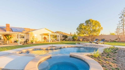 A breathtaking outdoor sanctuary with a pool, grassy surroundings, a fire pit, and conversation seating. Photo