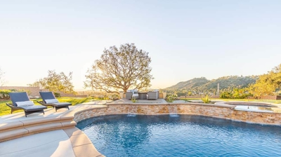 An enchanting outdoor haven with a pool, green grass, a fire pit, and cozy seating. Photo
