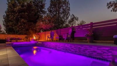 A spacious rectangular pool incorporating a spa, positioned alongside a fire feature accompanied by ample seating arrangements. Photo