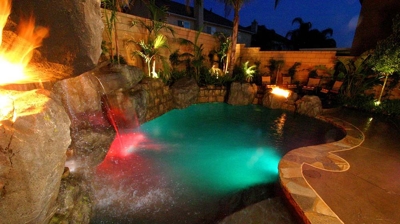 A nocturnal oasis with a tropical pool aglow amidst flickering flames. Photo