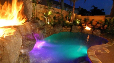 A nighttime retreat where the tropical pool shimmers under the glow of fiery accents. Photo