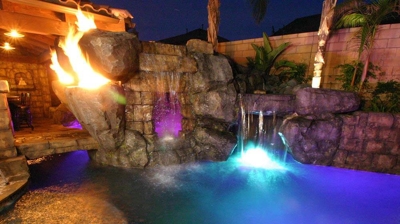 An evening paradise with the tropical pool illuminated by both lights and dancing flames. Photo