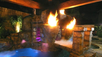 Tropical island themed pool with a bridge and fire features. Photo