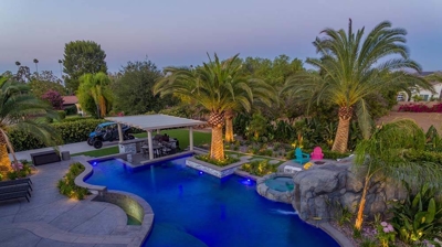Aerial view of blue lit pool and patio alongside a serene view. Photo