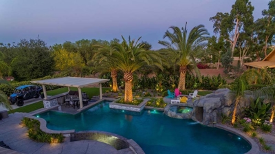 Aerial view of lit pool and patio alongside a serene view. Photo