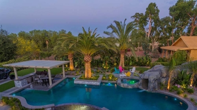 Aerial view of lit pool and patio alongside a serene view. Photo