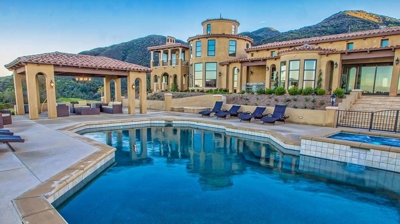 Luxury home embodied by clear pool and lawn chairs. Photo
