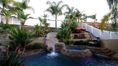 Lit up outdoor pool and jacuzzi with a serene green view. Photo