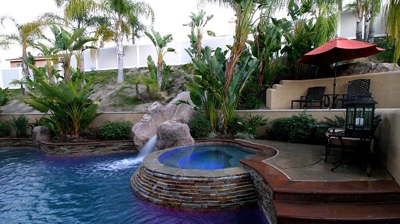 Lit up outdoor pool and jacuzzi with a serene green view. Photo